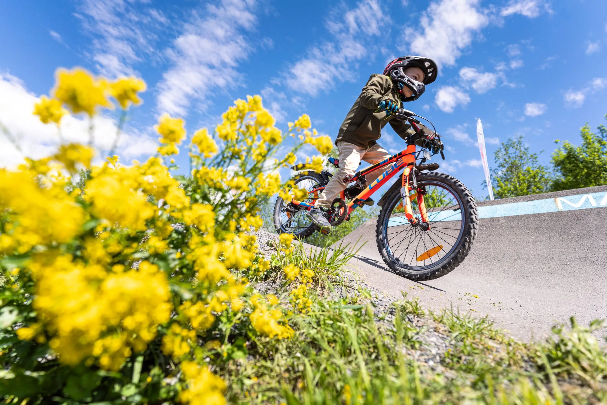 Ein Kind hinter einer Blume auf einem Pumptrack.