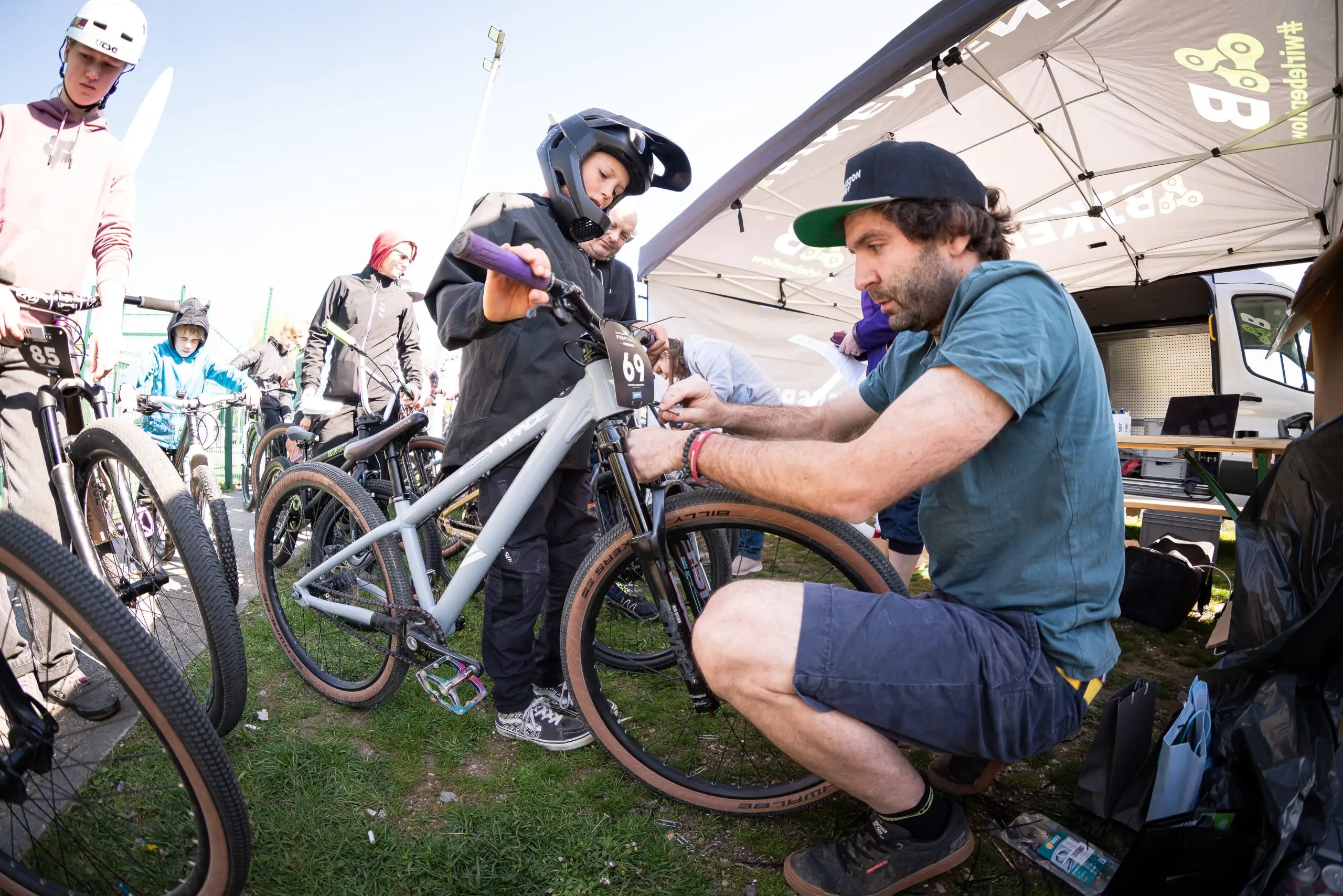 Mehrere Mountainbiker basteln etwas an einem Dirtbike und bringen die Startnummern an.