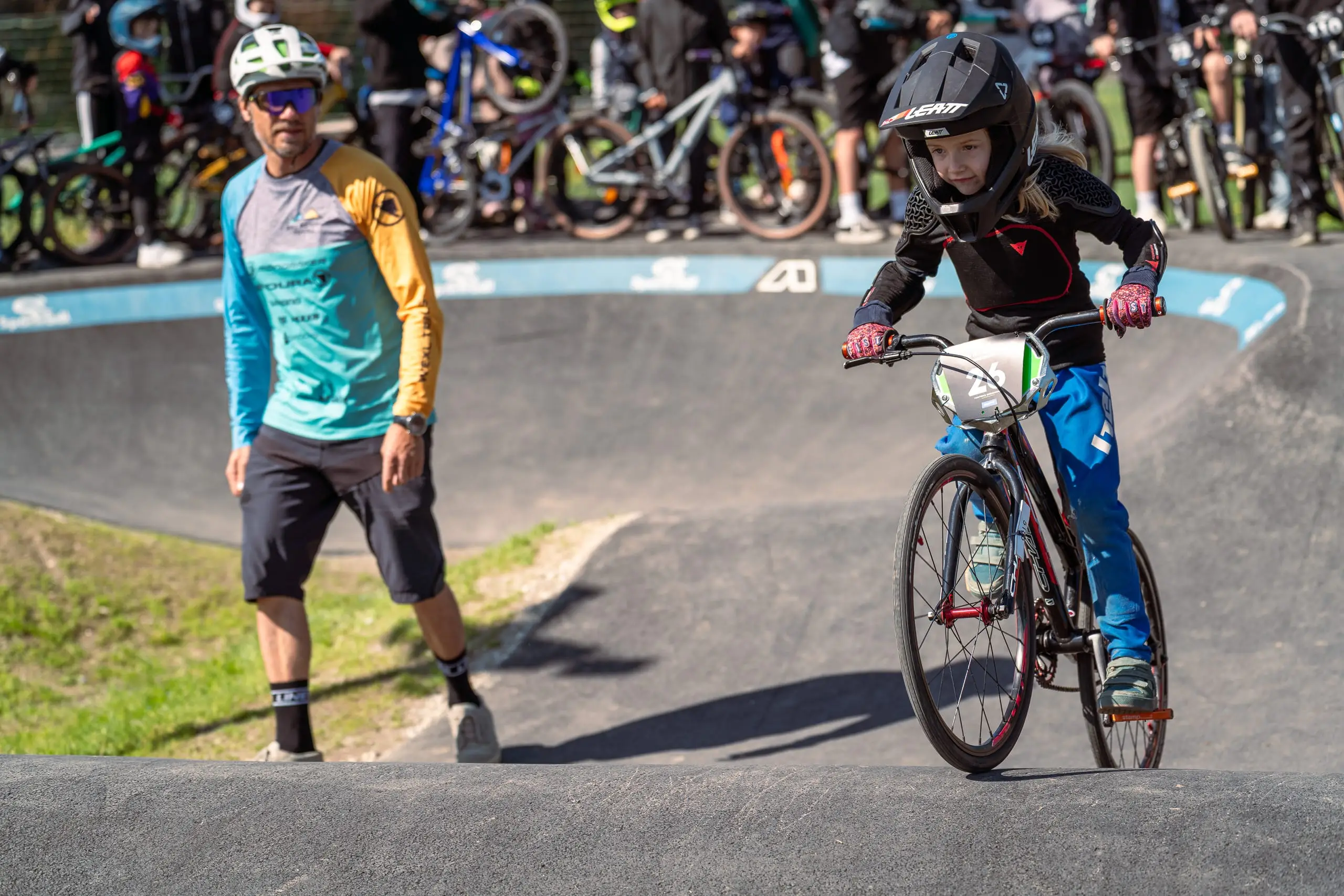 Ein Mountainbiker auf einem Pumptrack gefolgt von einem Bike Guide.