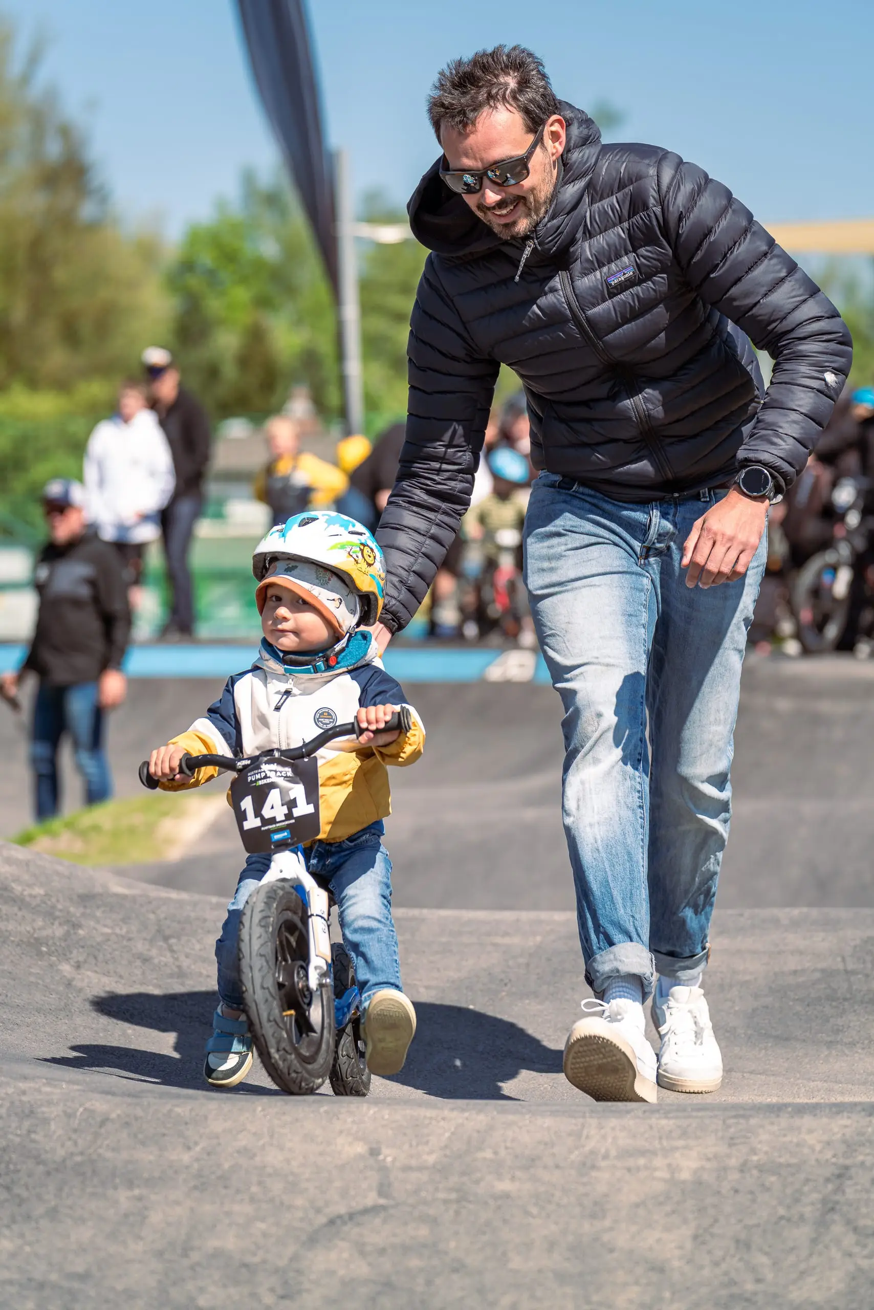 Ein Kind auf einem Mountainbike mit seinem Vater auf einem Pumptrack.