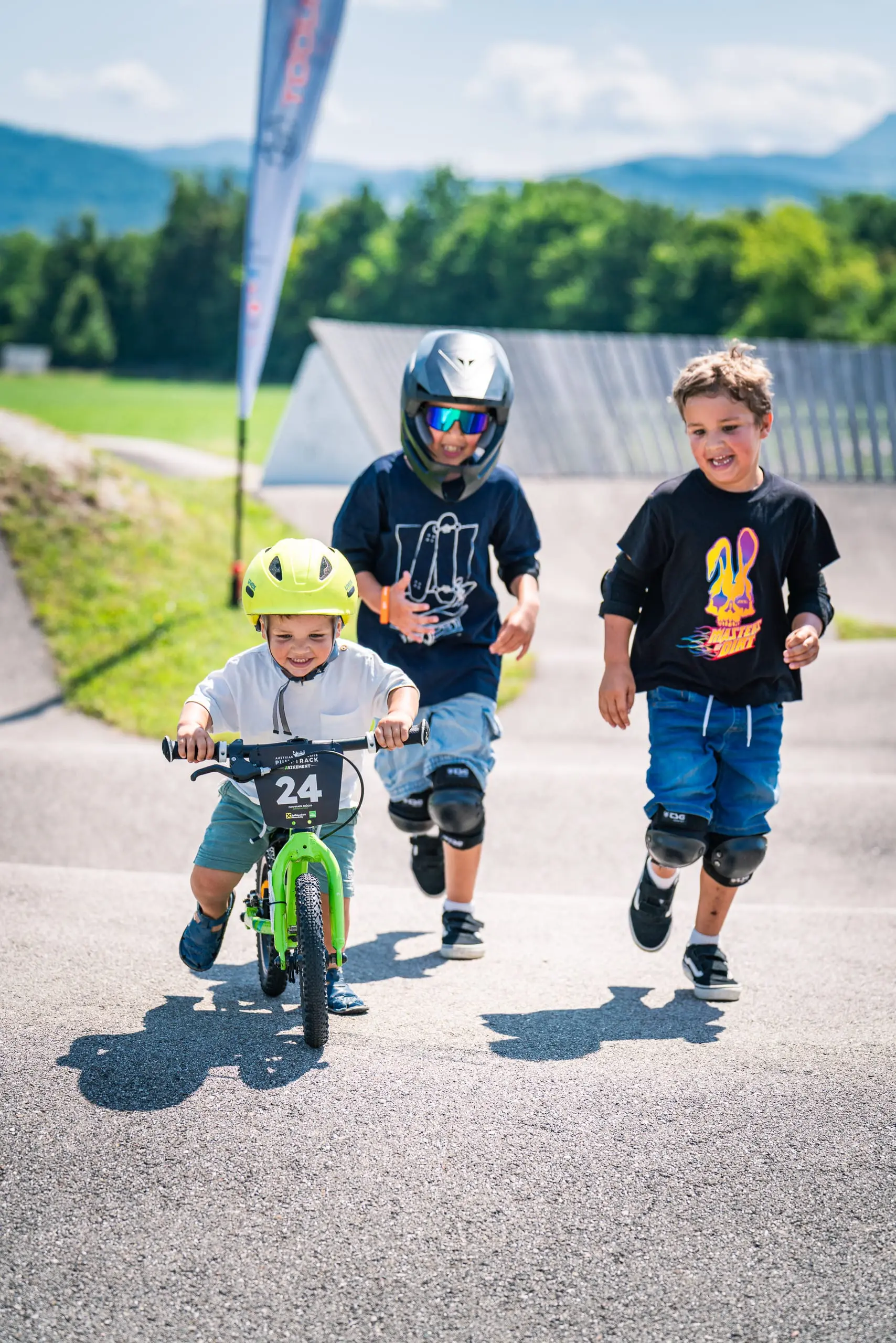 Drei Mountainbiker auf einem Pumptrack.