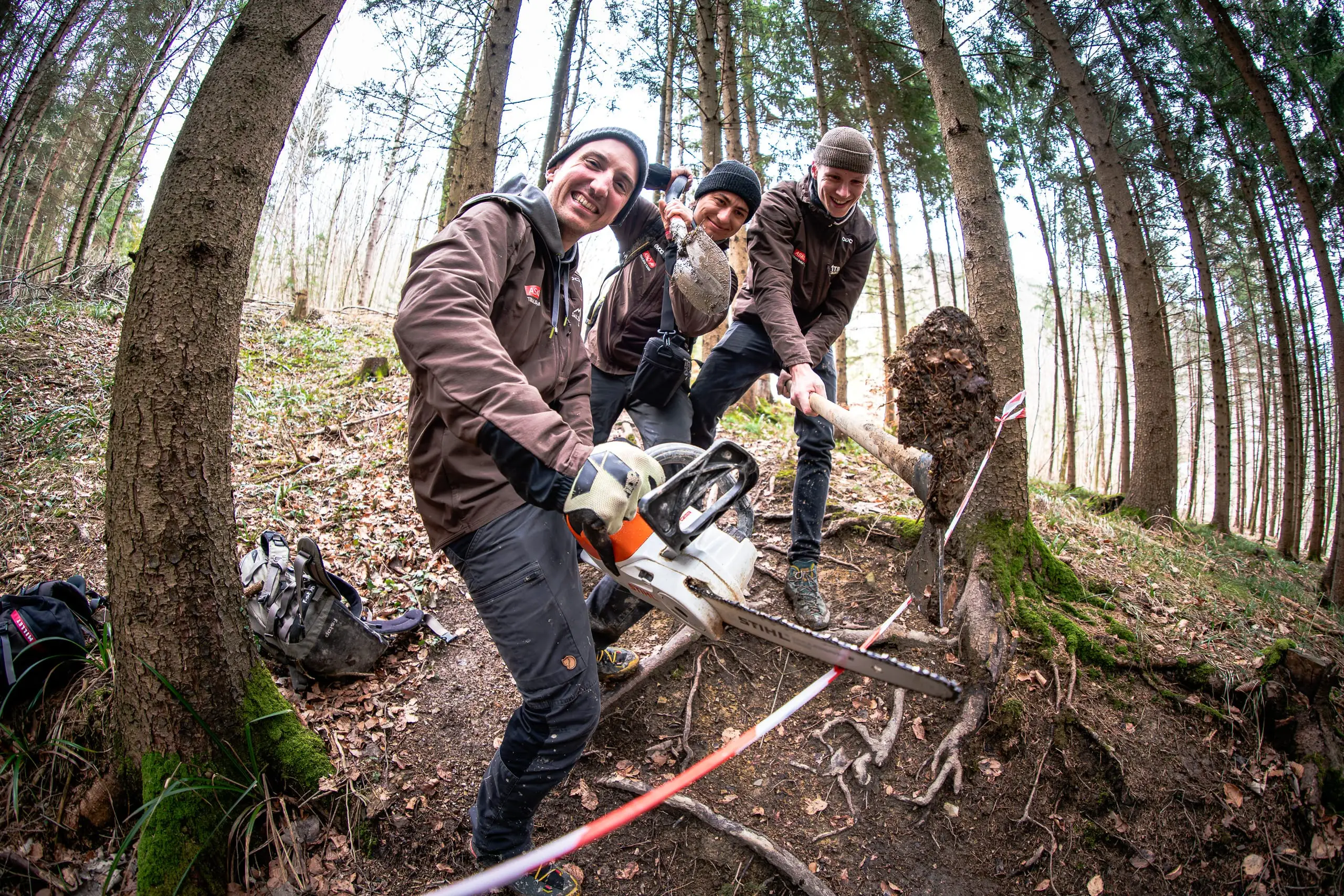 Eine Gruppe Mountainbiker posiert mit Werkzeugen auf einem Trail.