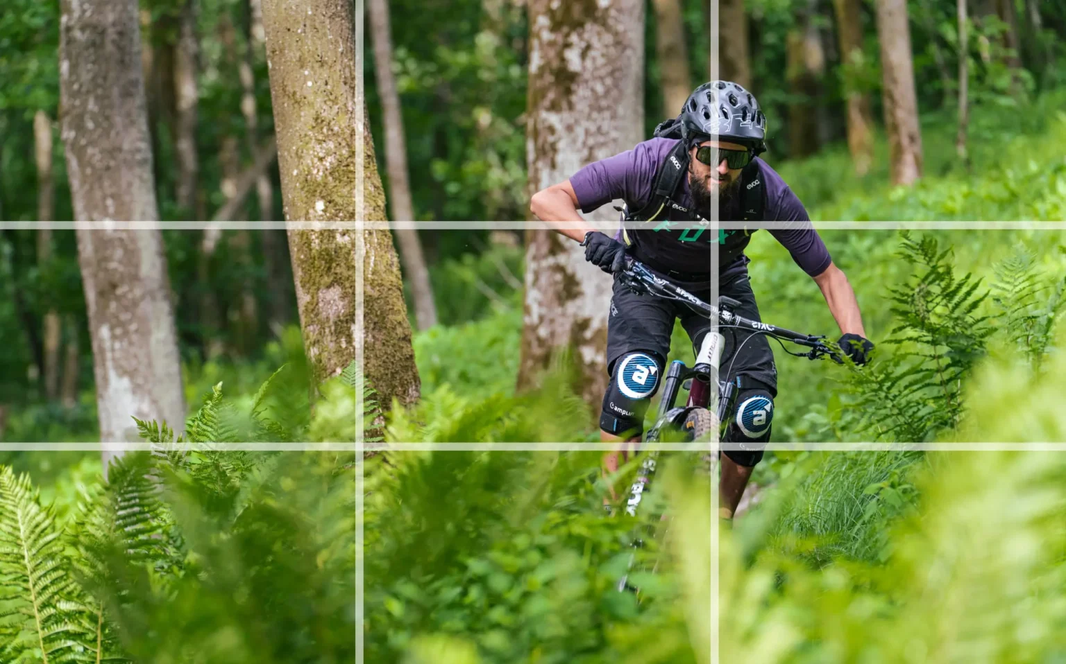 Ein Mountainbiker fährt durch einen Wald. Um die Drittel-Regel zu veranschaulichen, wurde darüber ein Overlay-Gitter gelegt.